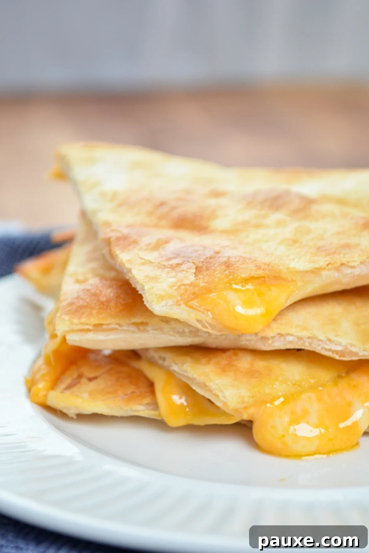 A stack of three air fryer cheese quesadilla triangles, with a focus on crispy edges.