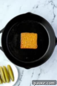 Zesty Brined Cheese Bites 11 A skillet with a melted cheese slice in the middle, showing it beginning to bubble and crisp.