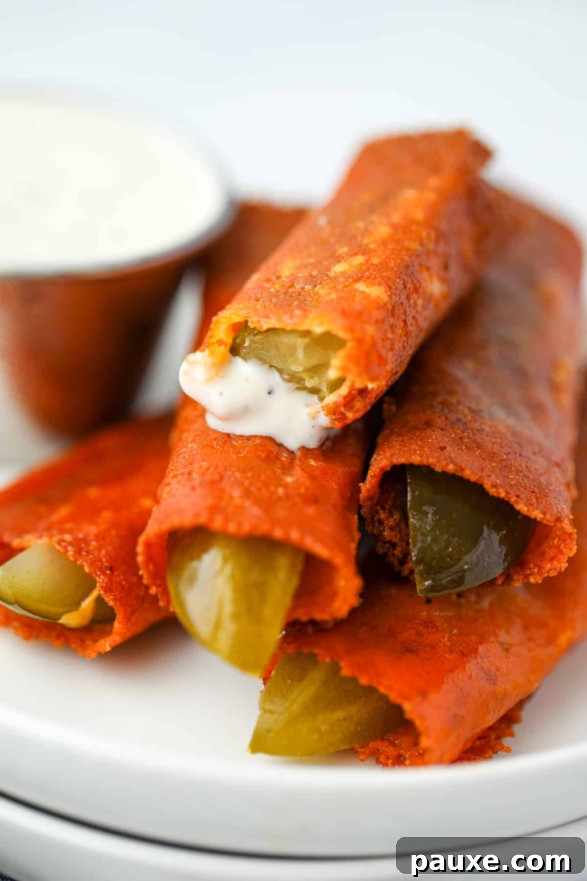 Zesty Brined Cheese Bites 9 A stack of cheesy fried pickles with the top one being dipped in ranch dressing, emphasizing the delicious, crispy texture.