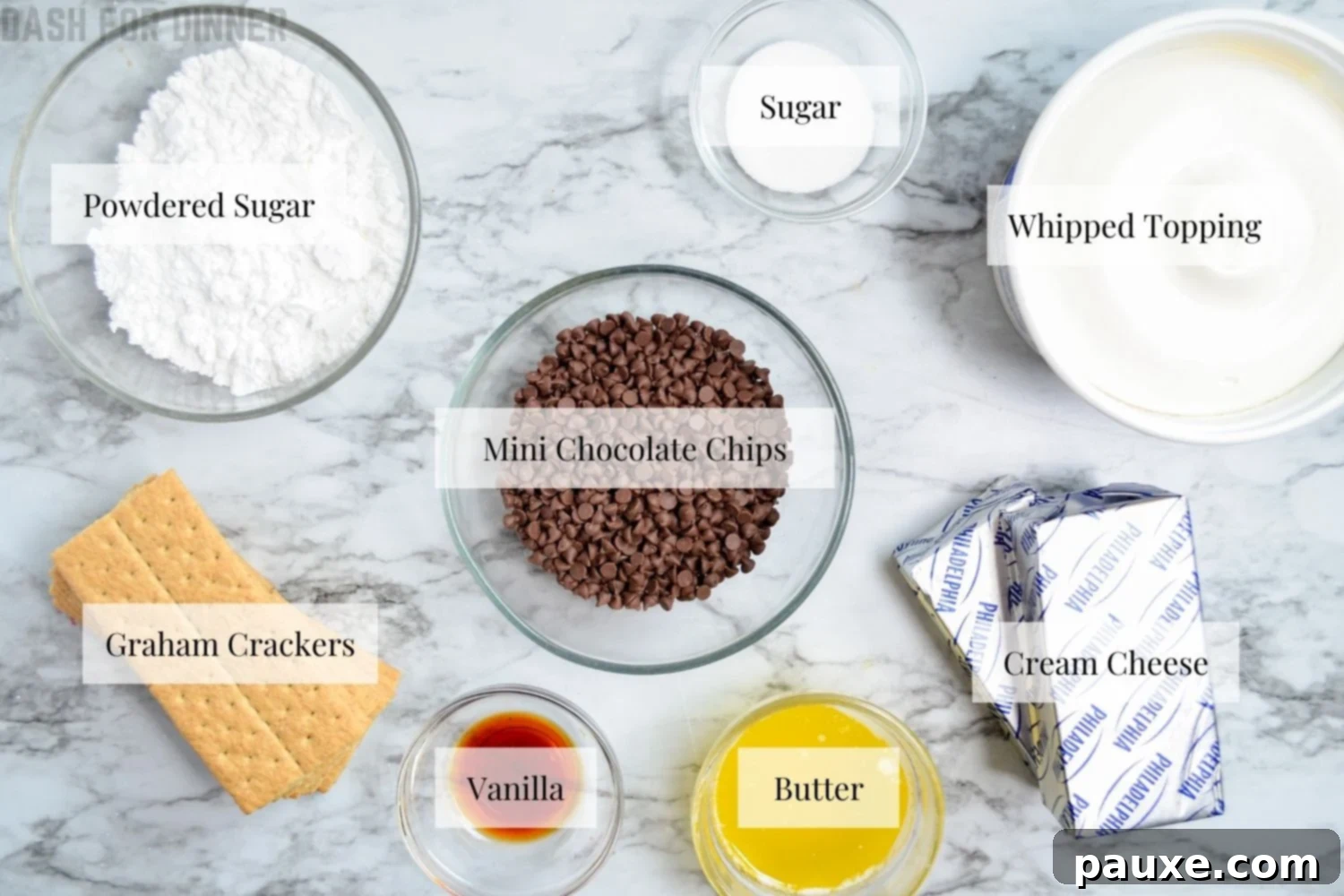 Easy No-Bake Chocolate Chip Cheesecake 3 A selection of ingredients laid out on a wooden surface, including graham crackers, cream cheese, sugar, butter, and chocolate chips, ready for making a no-bake chocolate chip cheesecake.