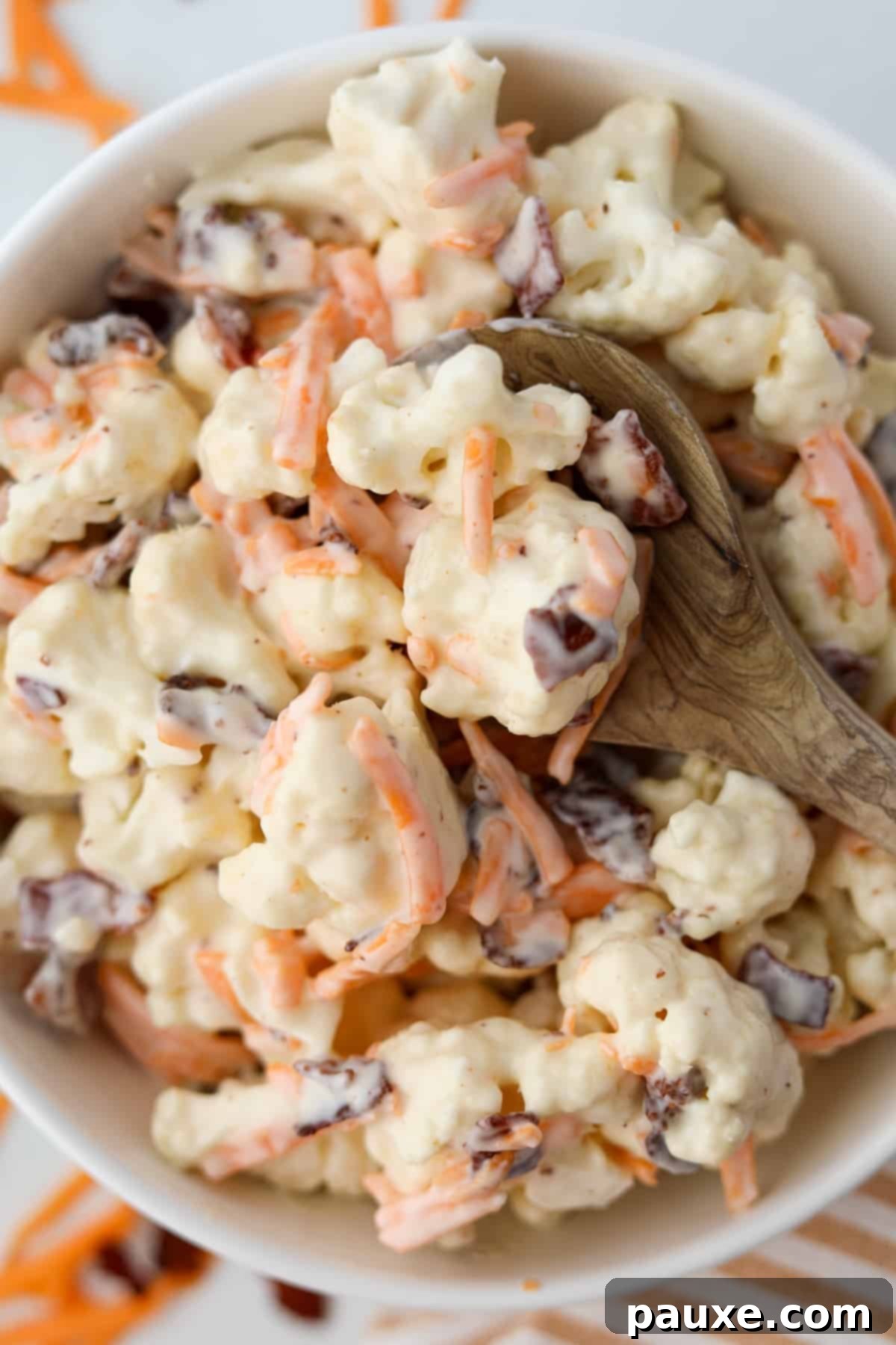 Spiced Cauliflower Salad with Tahini 9 A wooden spoon holding several cauliflower florets covered in a creamy dressing.