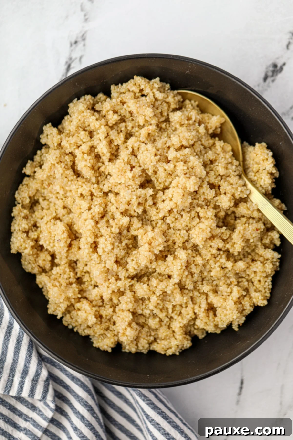 Effortless Instant Pot Quinoa 6 A golden spoon scooping cooked, fluffy quinoa from a black bowl.