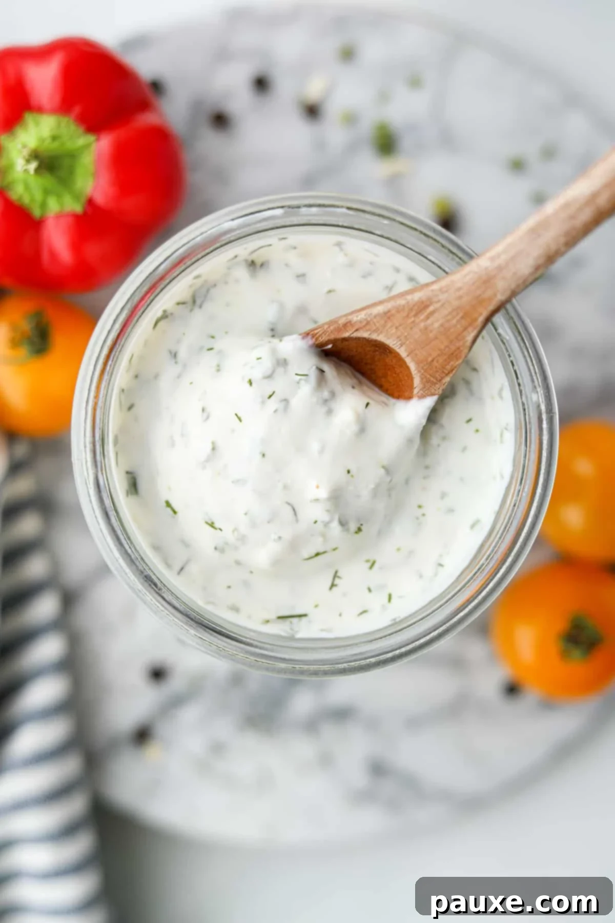 Healthy Greek Yogurt Ranch 2 Scooping ranch from a glass jar with a wooden spoon.