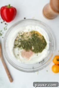 Healthy Greek Yogurt Ranch 11 A bowl of greek yogurt filled with various seasonings.
