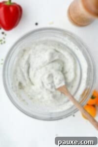 Healthy Greek Yogurt Ranch 12 A bowl of homemade salad dressing that's being stirred with a wooden spoon.