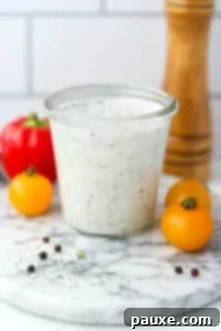 Healthy Greek Yogurt Ranch 13 A glass jar filled with homemade ranch dressing, with veggies in the background.