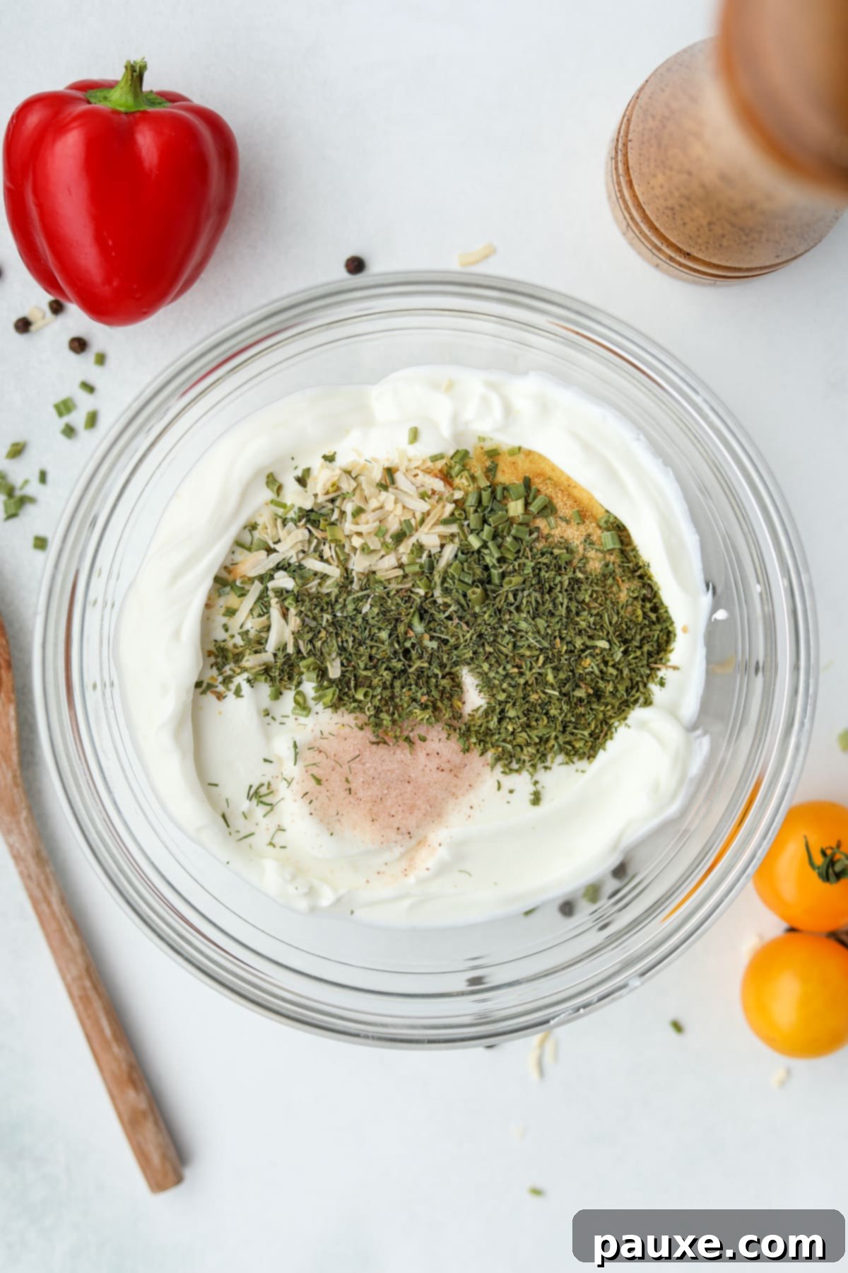 Healthy Greek Yogurt Ranch 4 A bowl of greek yogurt filled with various seasonings.