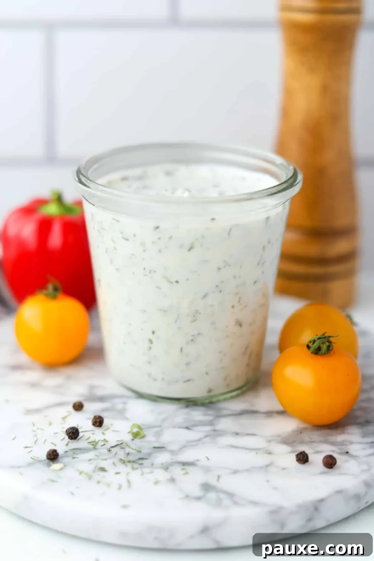 Healthy Greek Yogurt Ranch 7 A glass jar filled with homemade ranch dressing, with veggies in the background.
