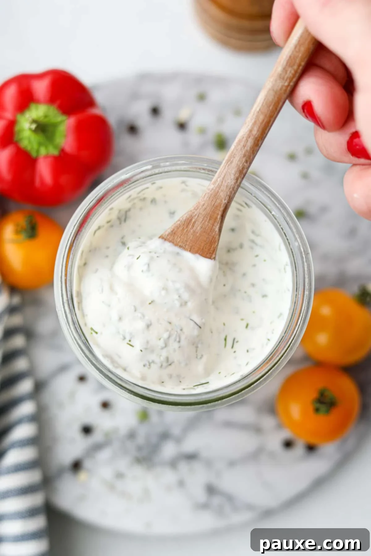 Healthy Greek Yogurt Ranch 8 Scooping ranch dressing from a jar with a small wooden spoon.