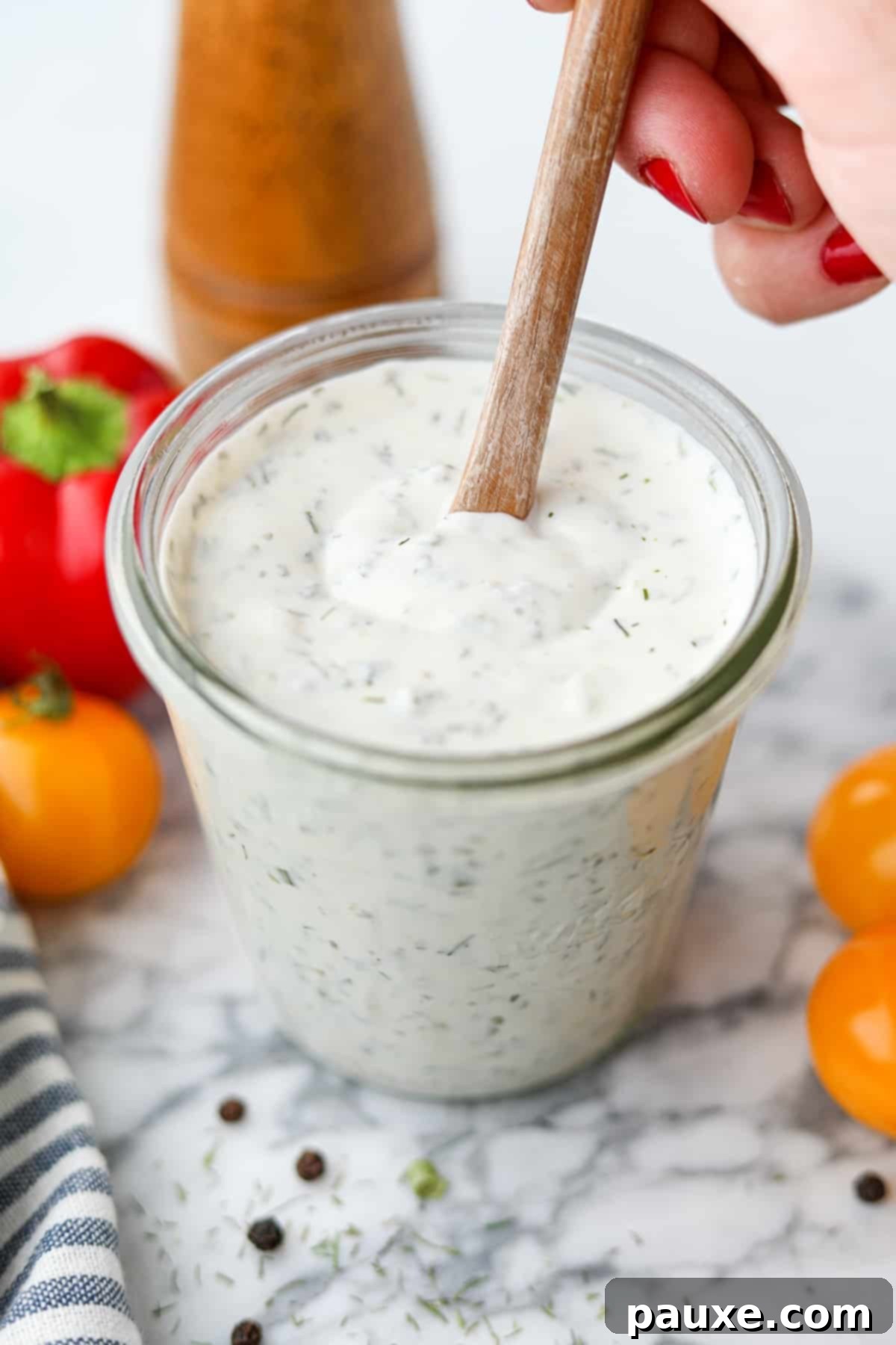 Healthy Greek Yogurt Ranch 9 Stirring ranch dressing in a glass jar.