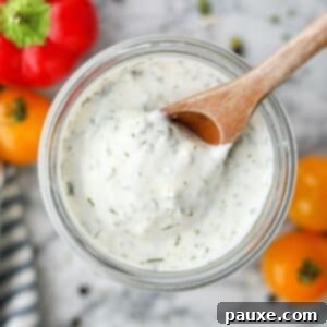 Healthy Greek Yogurt Ranch 10 Scooping ranch dressing from a glass jar with a wooden spoon.