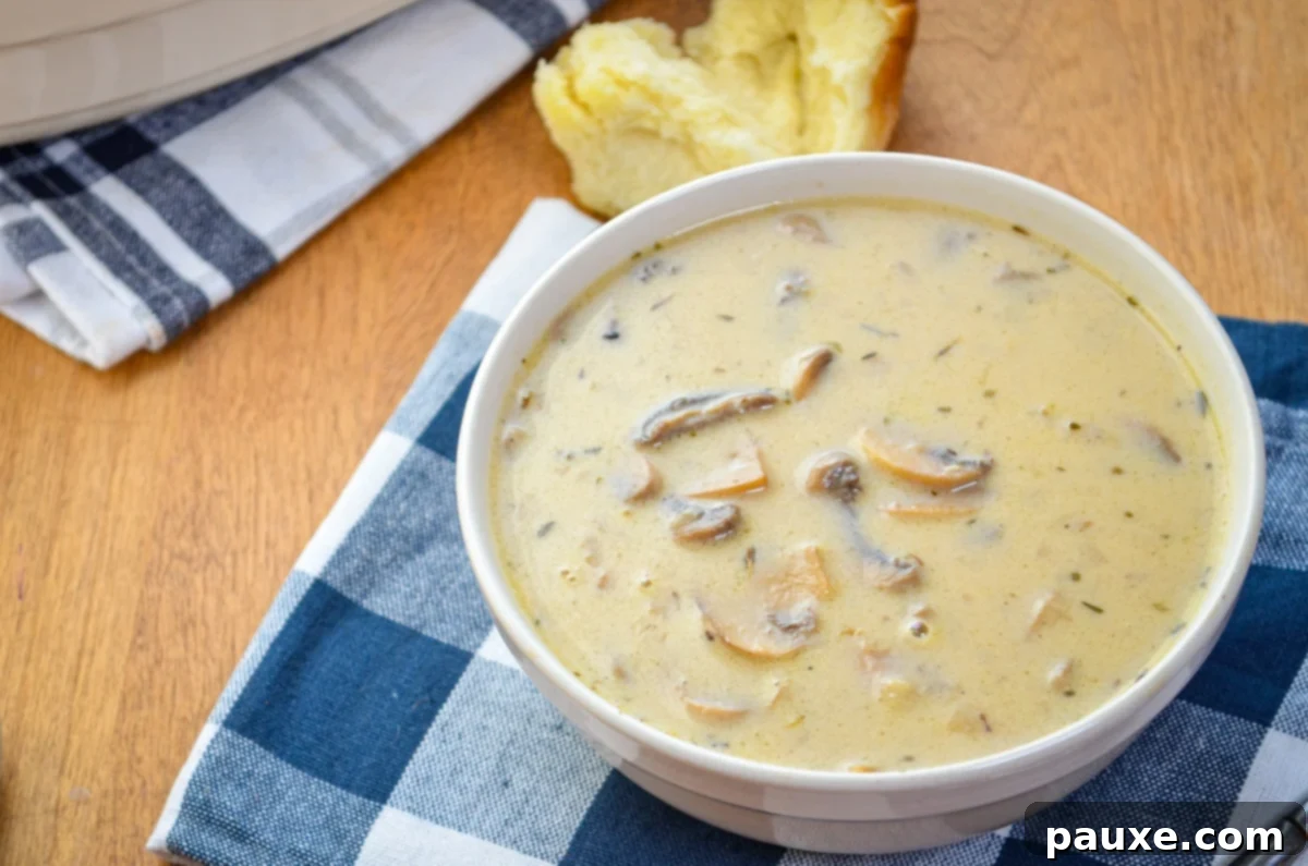 Instant Pot Creamy Mushroom Comfort 10 A bowl of cream of mushroom soup with a torn roll in the background.