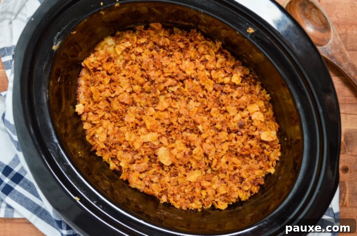 Slow Cooker Golden Cheesy Hash Brown Bake 2 A slow cooker full of cheesy hashbrown potatoes, topped with crushed cornflakes.