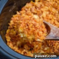 Slow Cooker Golden Cheesy Hash Brown Bake 12 A large wooden spoon scoops up a portion of funeral potatoes made in a slow cooker.
