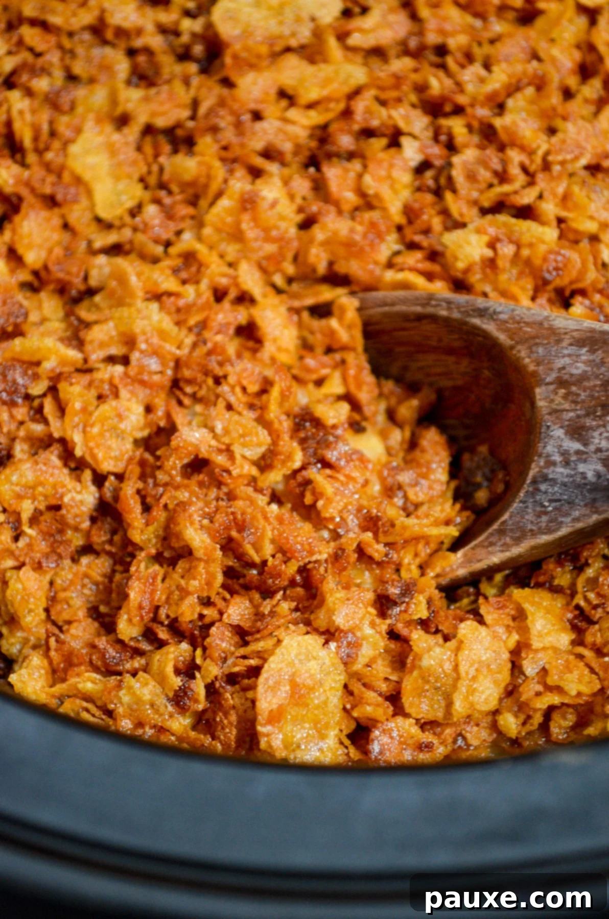 Slow Cooker Golden Cheesy Hash Brown Bake 4 Scooping a cornflake topped casserole from a slow cooker.
