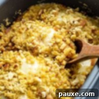 Creamy Swiss Chicken Slow Cooker Comfort 9 A wooden spoon taking a swiss cheese and stuffing topped chicken breast from a slow cooker.