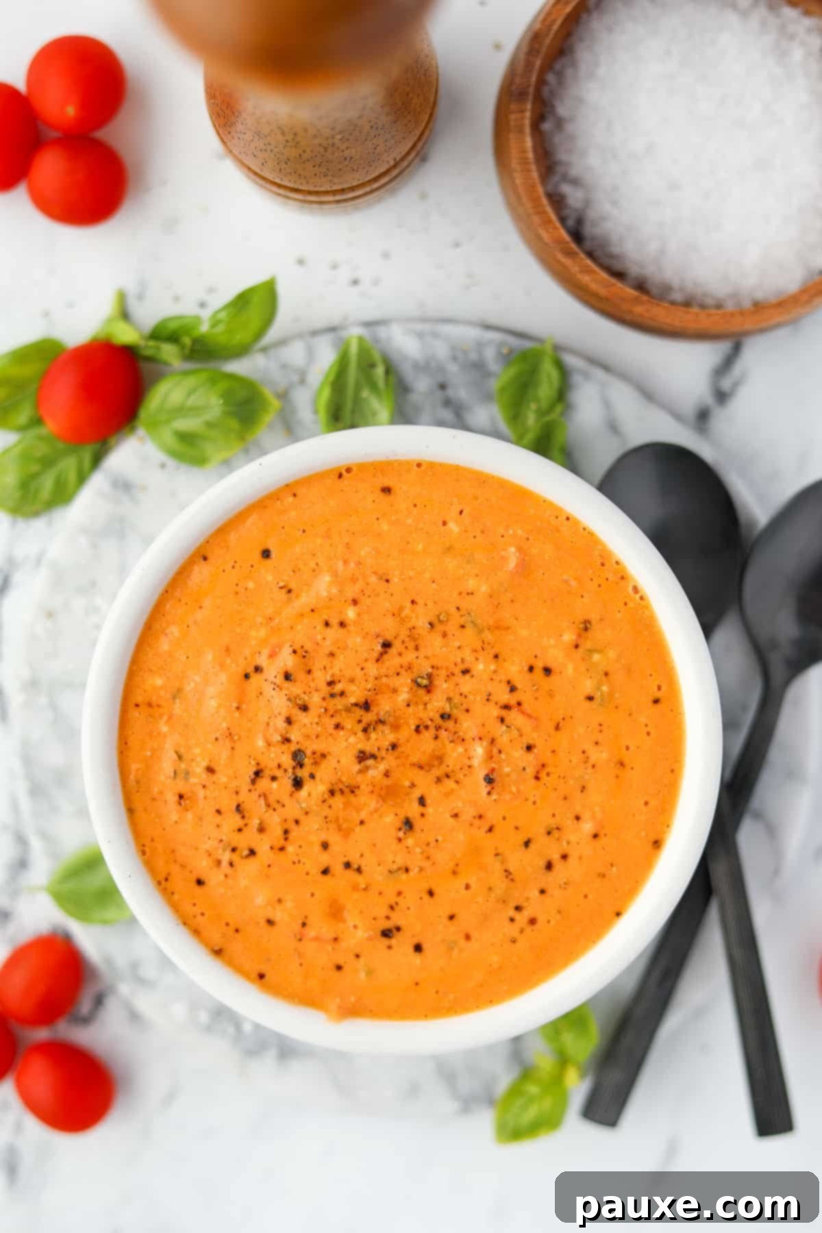 Roasted Feta Tomato Soup 2 A vibrant bowl of creamy tomato soup, elegantly garnished with fresh basil leaves and a sprinkle of feta, hinting at its rich flavor.