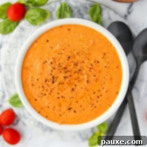 Roasted Feta Tomato Soup 8 A bowl of creamy tomato soup with cherry tomatoes and basil around the outside, enticing and delicious.