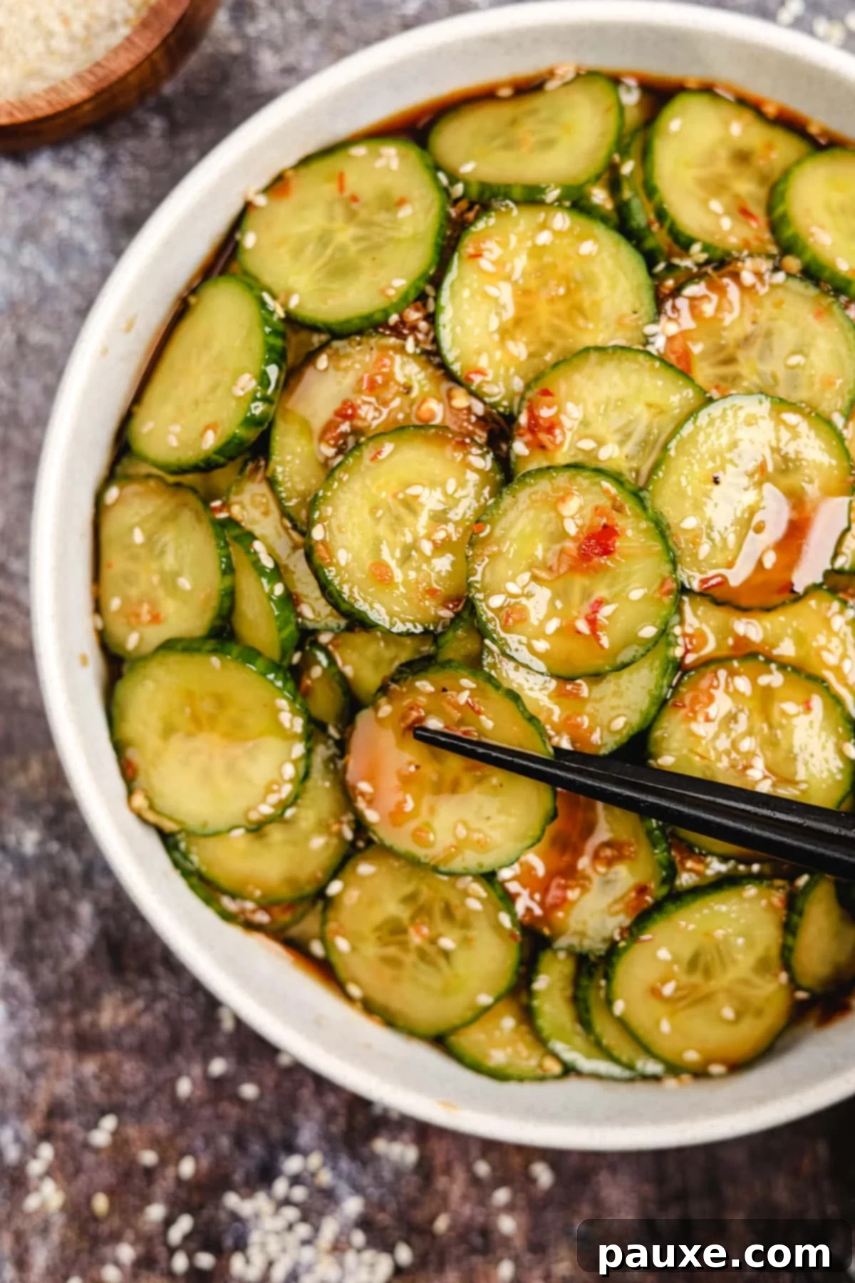 Chili Garlic Cucumber Crunch 2 A bowl of cucumber salad dotted with sesame seeds and chili pieces.