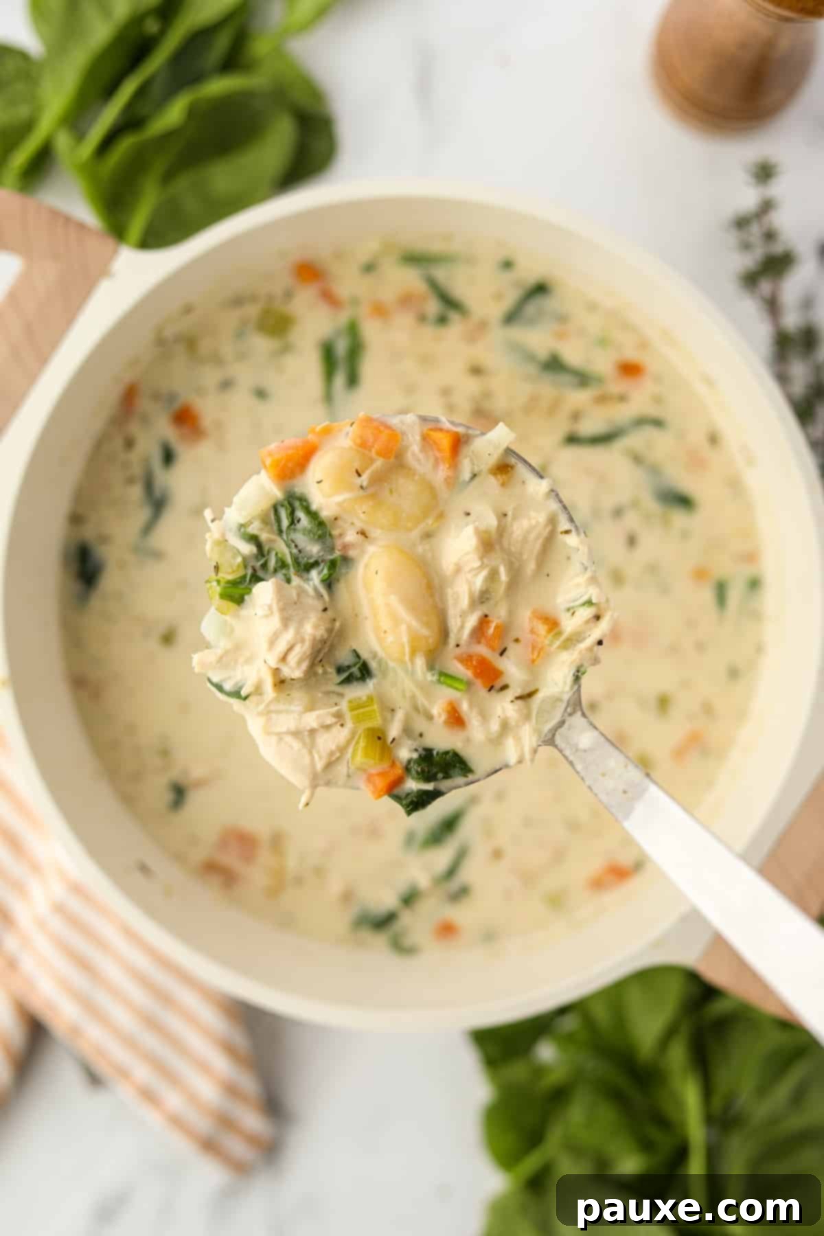 A ladle lifting creamy turkey gnocchi soup from a pot, showcasing the tender gnocchi and shredded turkey.