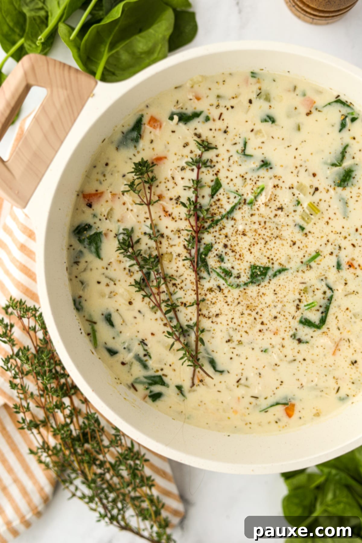 A pot brimming with creamy turkey gnocchi soup, elegantly garnished with fresh thyme sprigs.