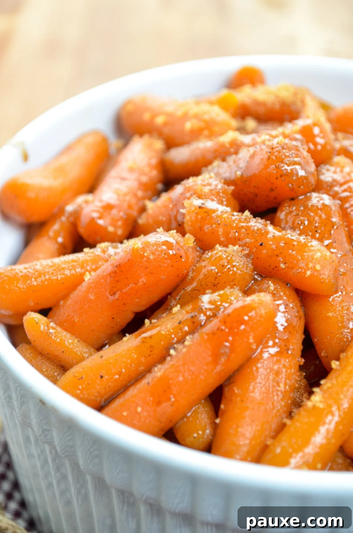 Caramelized Maple Brown Sugar Slow Cooker Carrots 2 A beautiful white serving dish, generously filled with slow cooker maple carrots, garnished with a sprinkle of extra brown sugar.