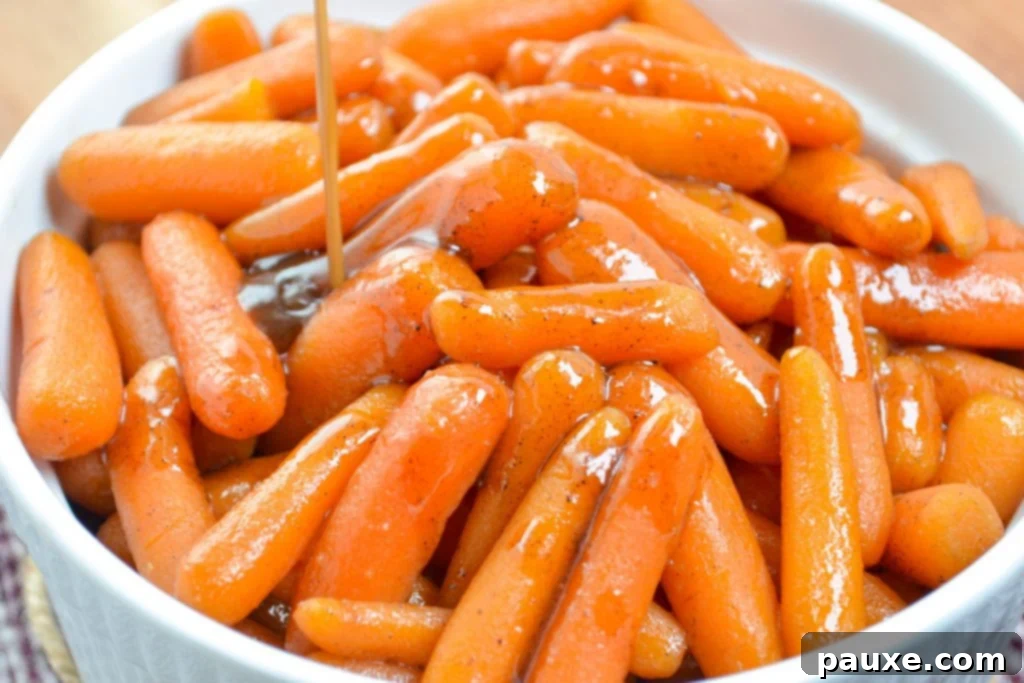 Caramelized Maple Brown Sugar Slow Cooker Carrots 7 A thick, rich glaze being carefully poured over a serving bowl filled with perfectly cooked baby carrots.