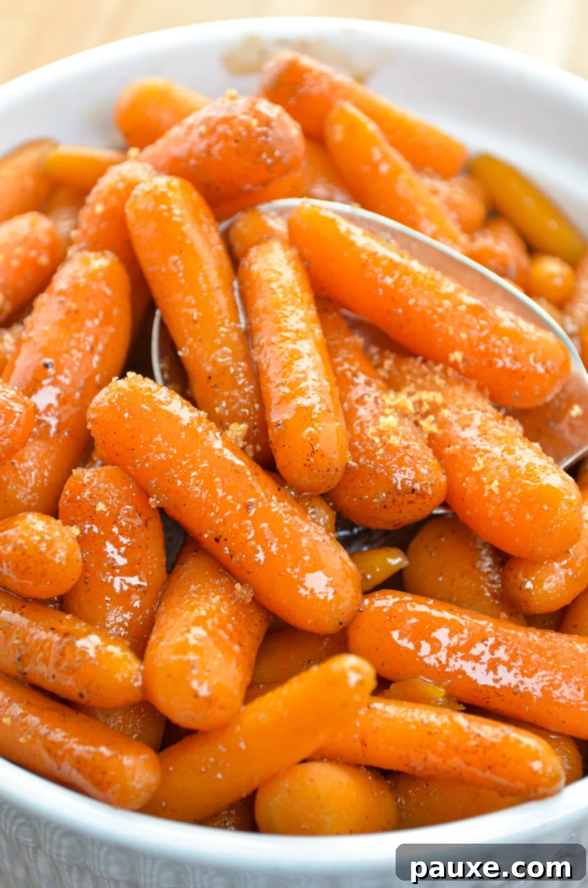Caramelized Maple Brown Sugar Slow Cooker Carrots 8 A pristine white serving dish showcasing a generous portion of maple glazed carrots, lightly sprinkled with additional brown sugar for garnish.