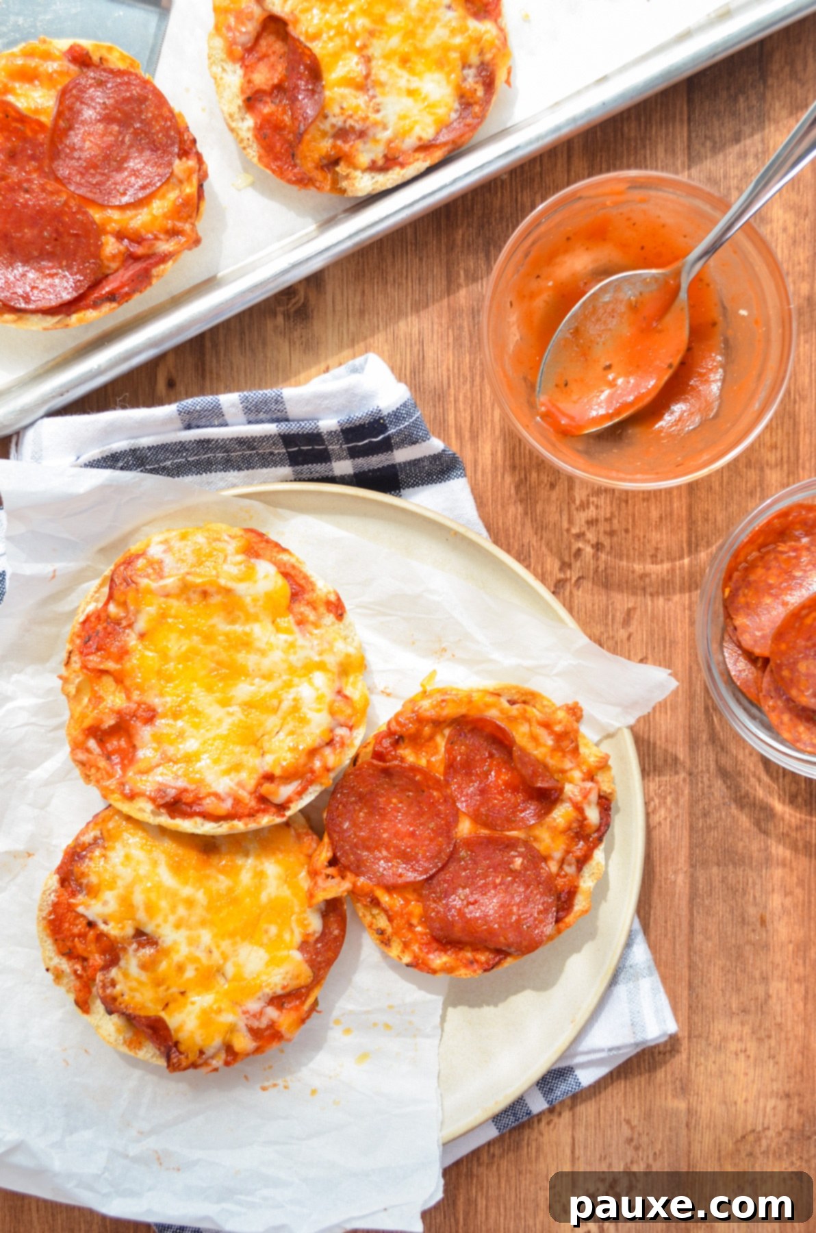 Quick Air Fryer Muffin Pizzas 3 Delicious English Muffin Pizzas on a plate, with a side of pizza sauce.