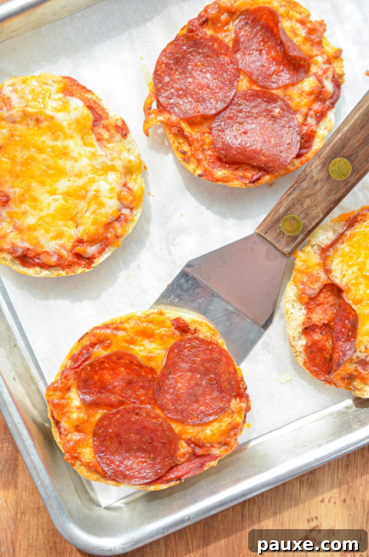 Quick Air Fryer Muffin Pizzas 7 Removing perfectly cooked English muffin pizzas from the air fryer with a spatula.