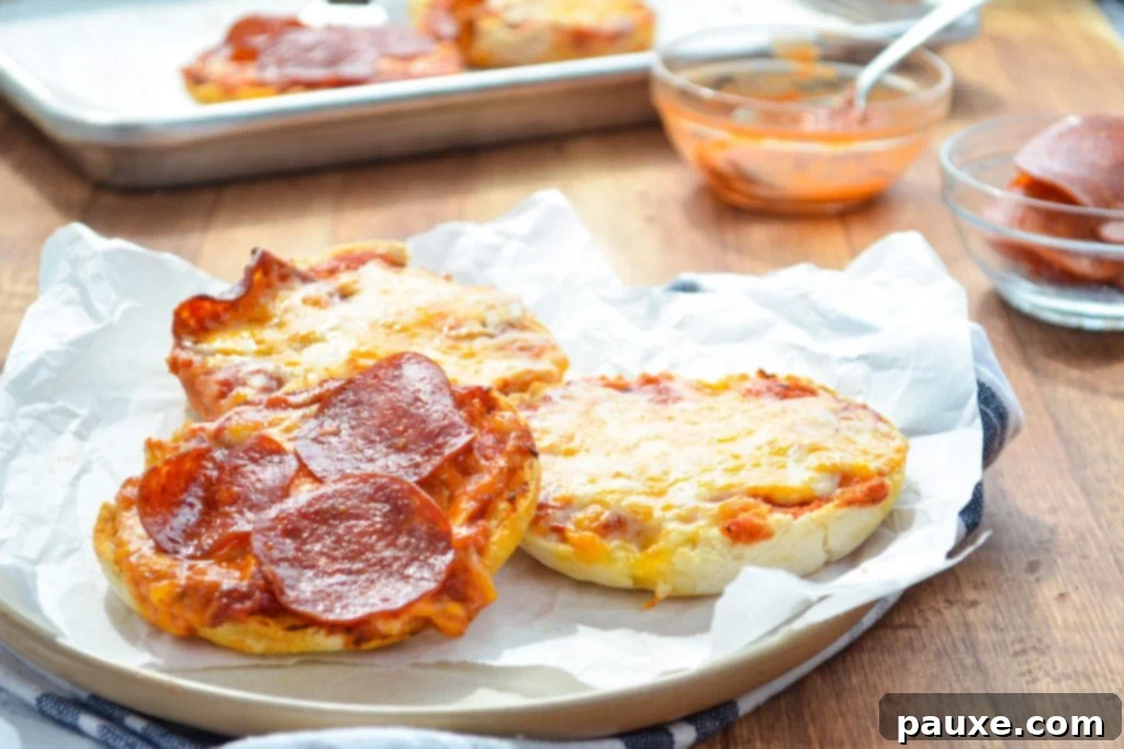 Quick Air Fryer Muffin Pizzas 9 A plate of freshly cooked English muffin pizzas, with more prepared on a baking sheet in the background.