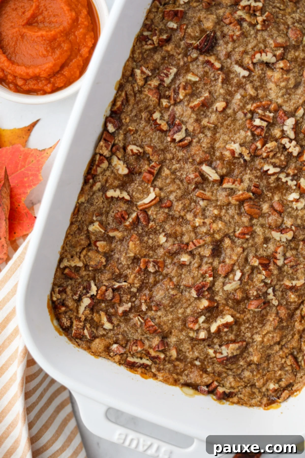 Golden Pumpkin Delight 2 A white baking dish filled with a creamy pumpkin casserole topped with golden pecans and brown sugar streusel, ready to be served for a holiday meal.