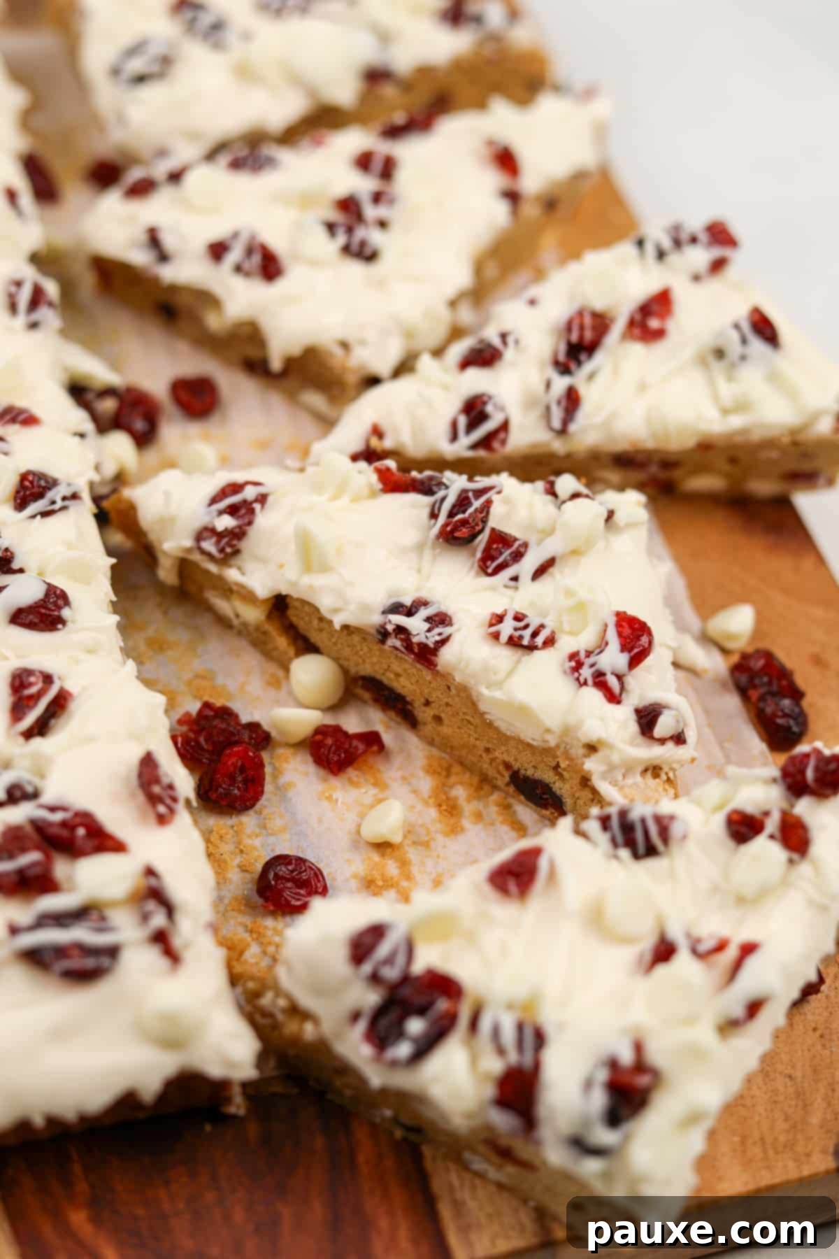 Ruby Red Cranberry Blondies 2 Triangle cookie bars topped with cream cheese frosting and dried cranberries.