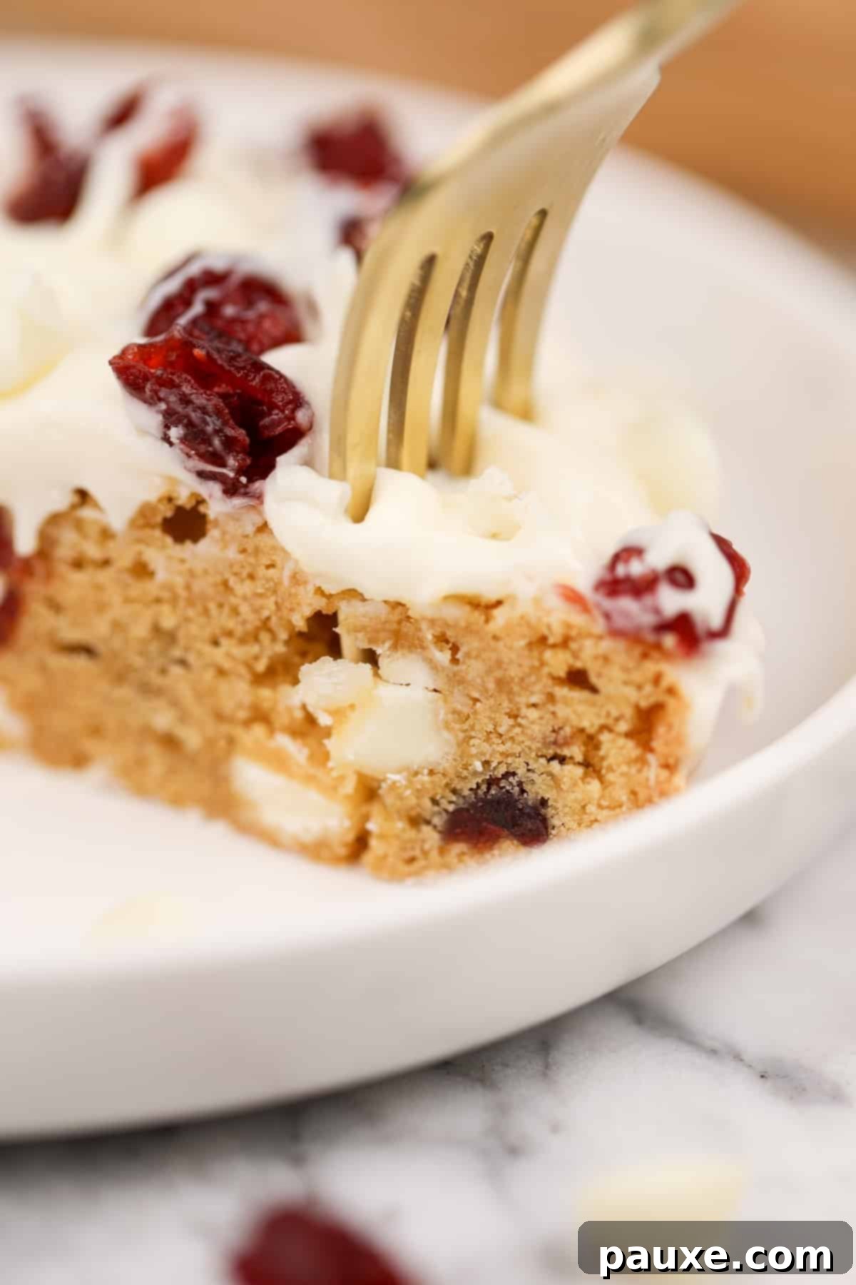 Ruby Red Cranberry Blondies 11 A fork sinking into a soft blondie layer that's topped with cream cheese frosting.