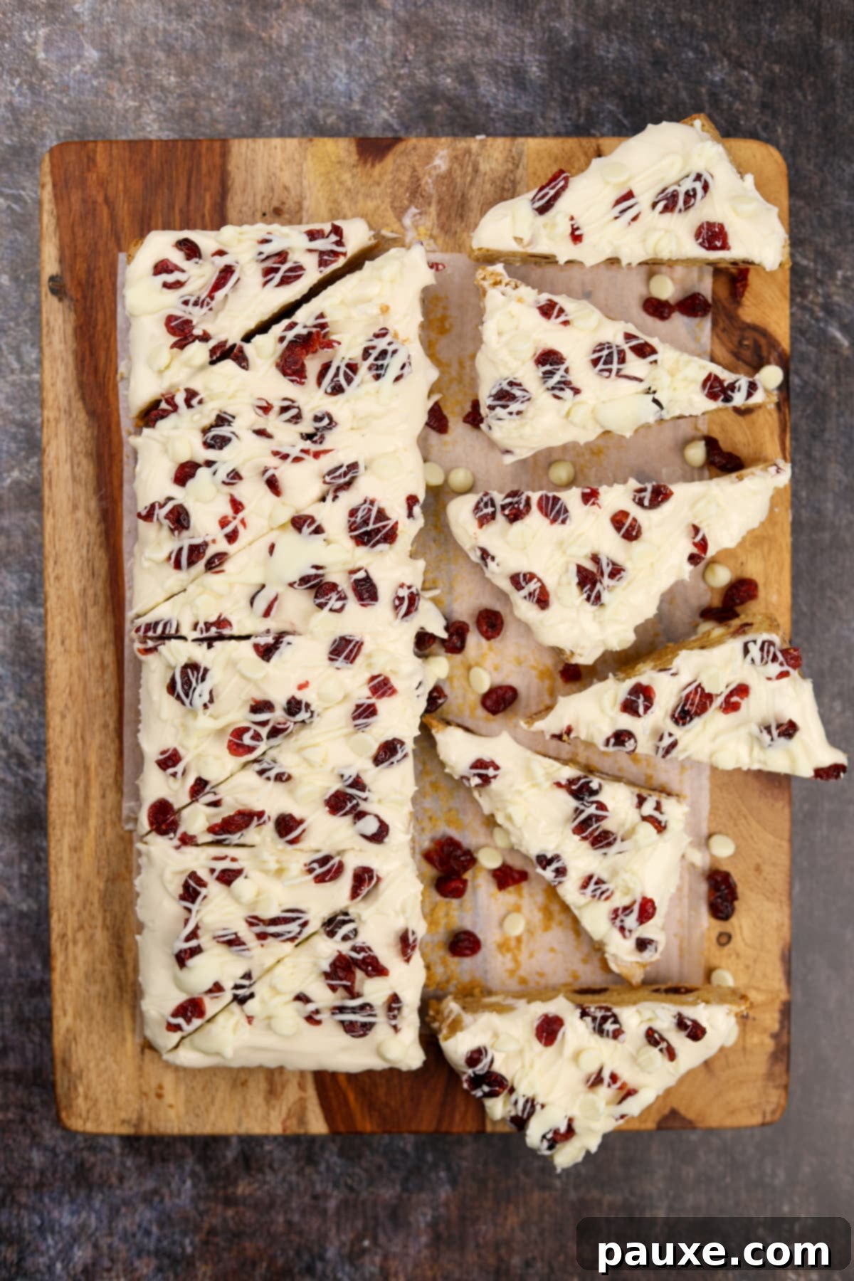 Ruby Red Cranberry Blondies 8 Slicing frosted blondies into triangles on a wooden cutting board.