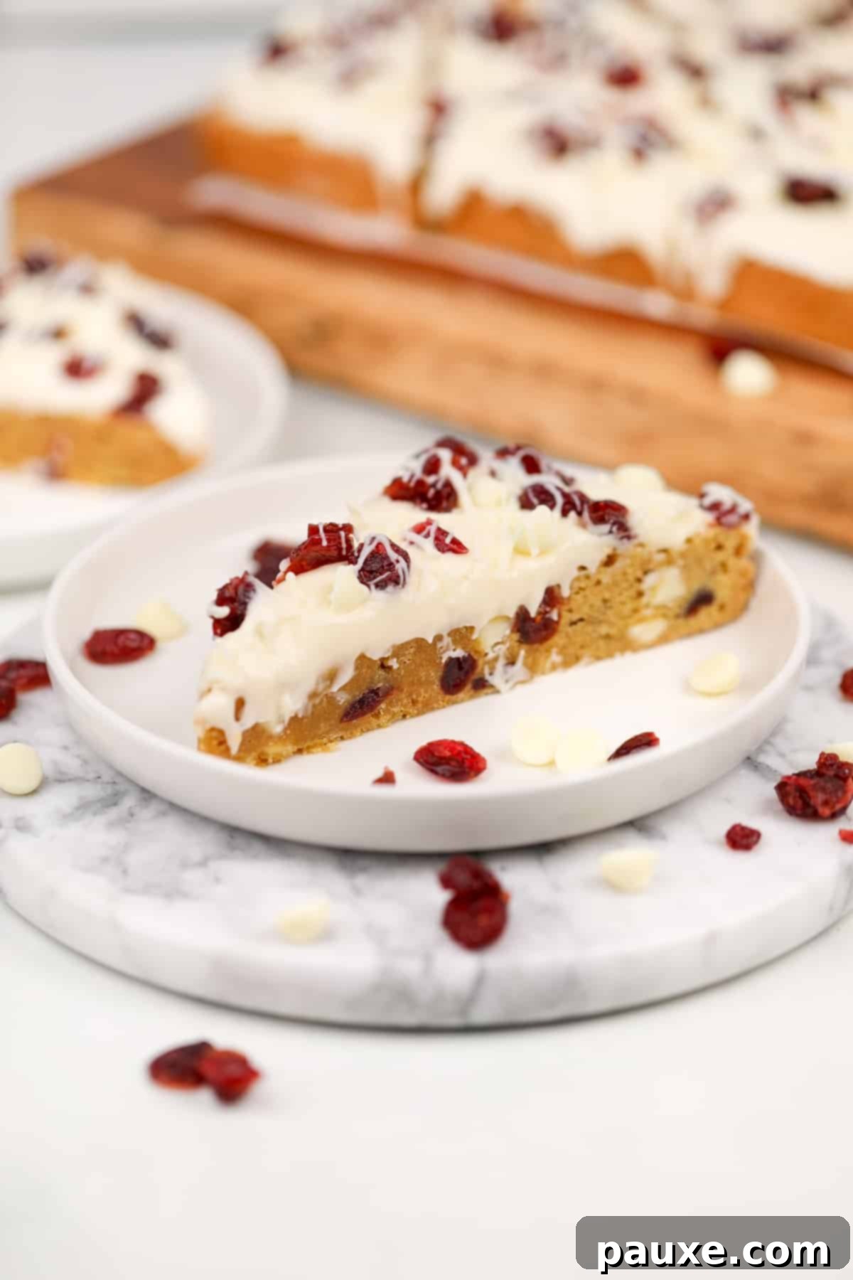 Ruby Red Cranberry Blondies 10 A triangular blondie bar topped with cream cheese frosting and dried cranberries.