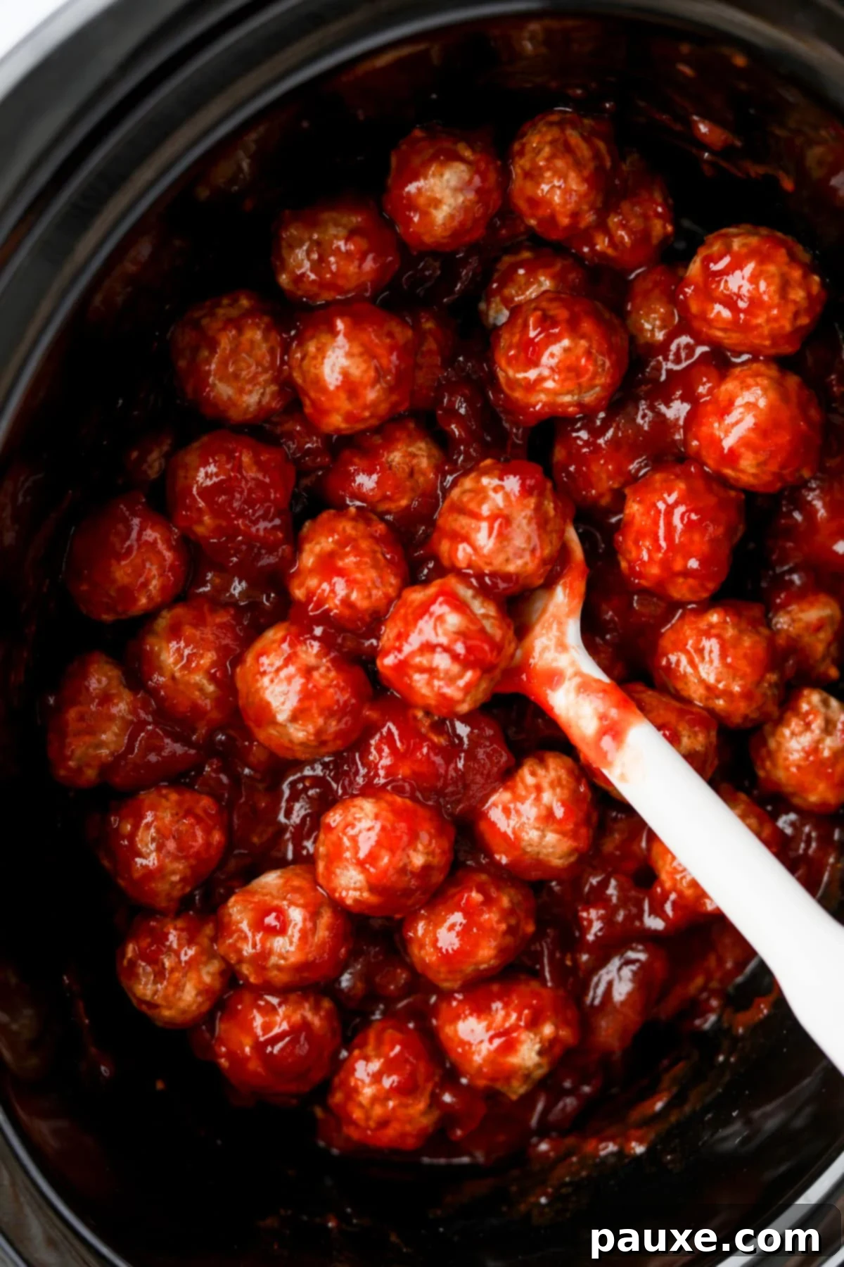 Slow Cooker Cranberry Glazed Meatballs 5 An oval crock pot filled with saucy meatballs.