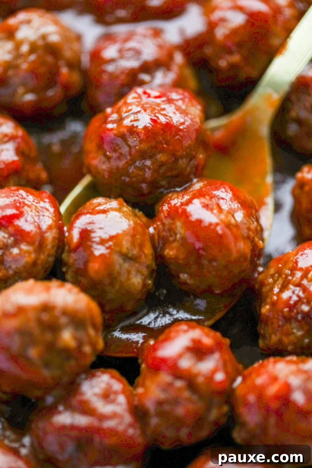 Slow Cooker Cranberry Glazed Meatballs 6 A spoon taking several saucy meatballs from a slow cooker.