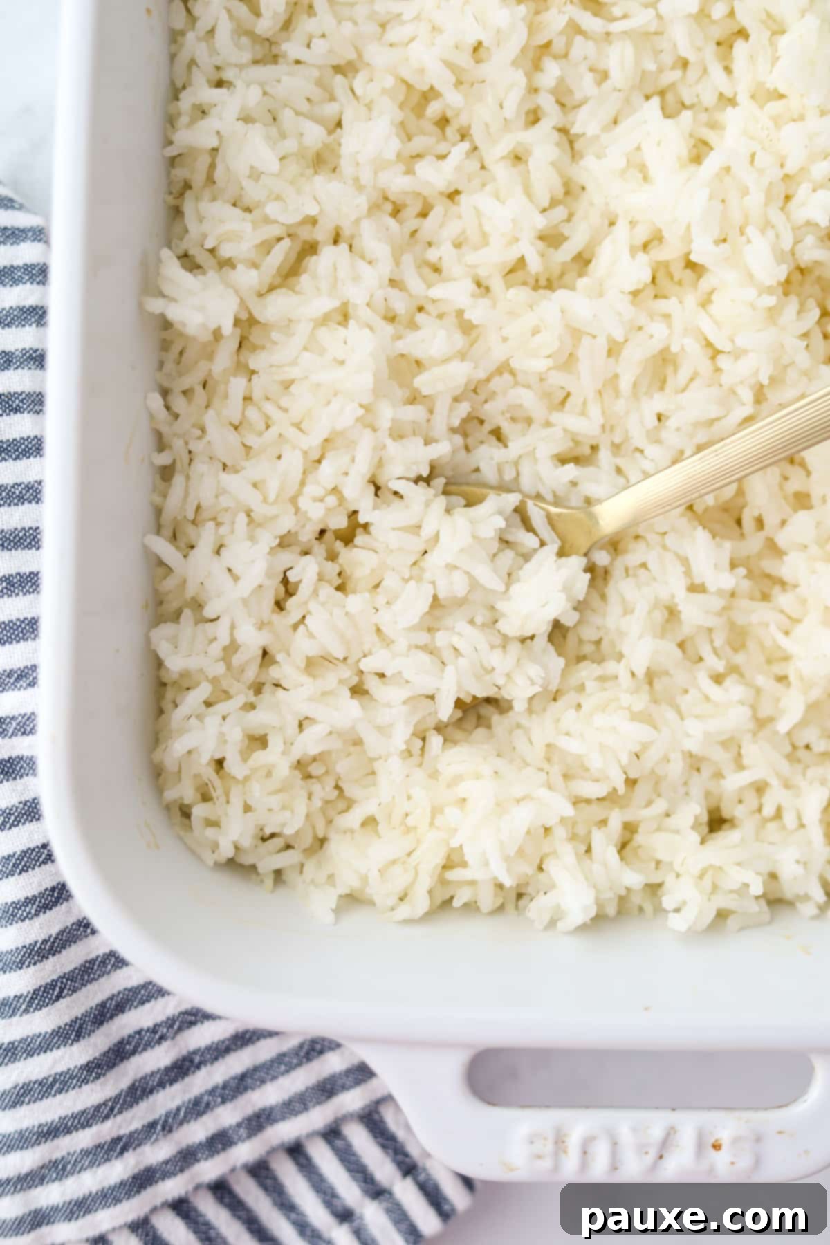 Golden Baked Rice 2 A spoon scooping perfectly cooked, fluffy rice from a baking dish, highlighting the steam and tender texture.