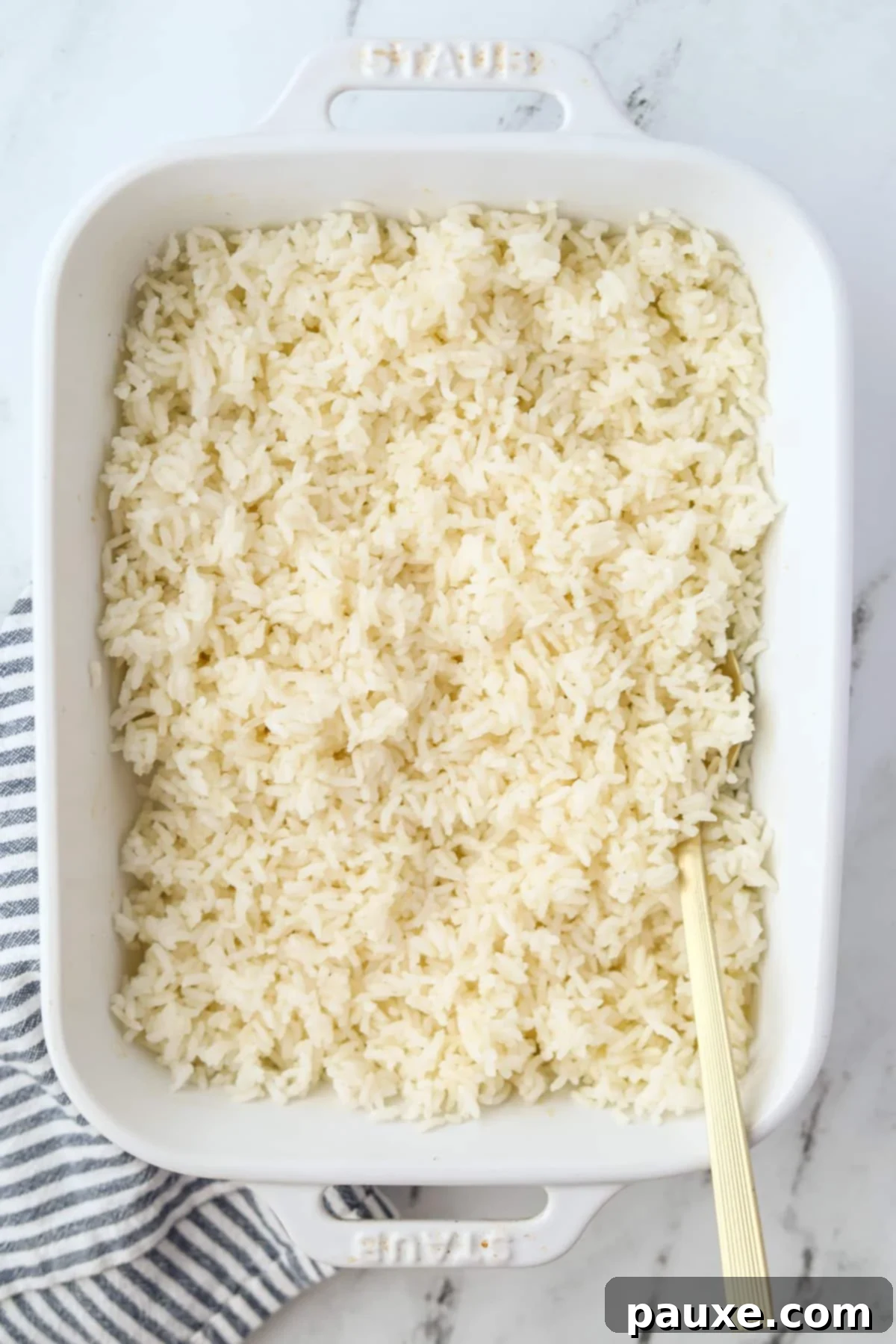 Golden Baked Rice 5 A baking dish filled with fluffy baked rice, with a serving spoon resting on the side, ready to be enjoyed.