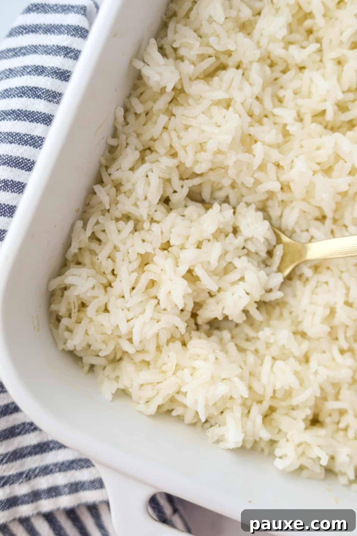 Golden Baked Rice 6 A baking dish filled with perfectly fluffy oven baked rice, with a serving spoon taking a portion, ready to be dished out.