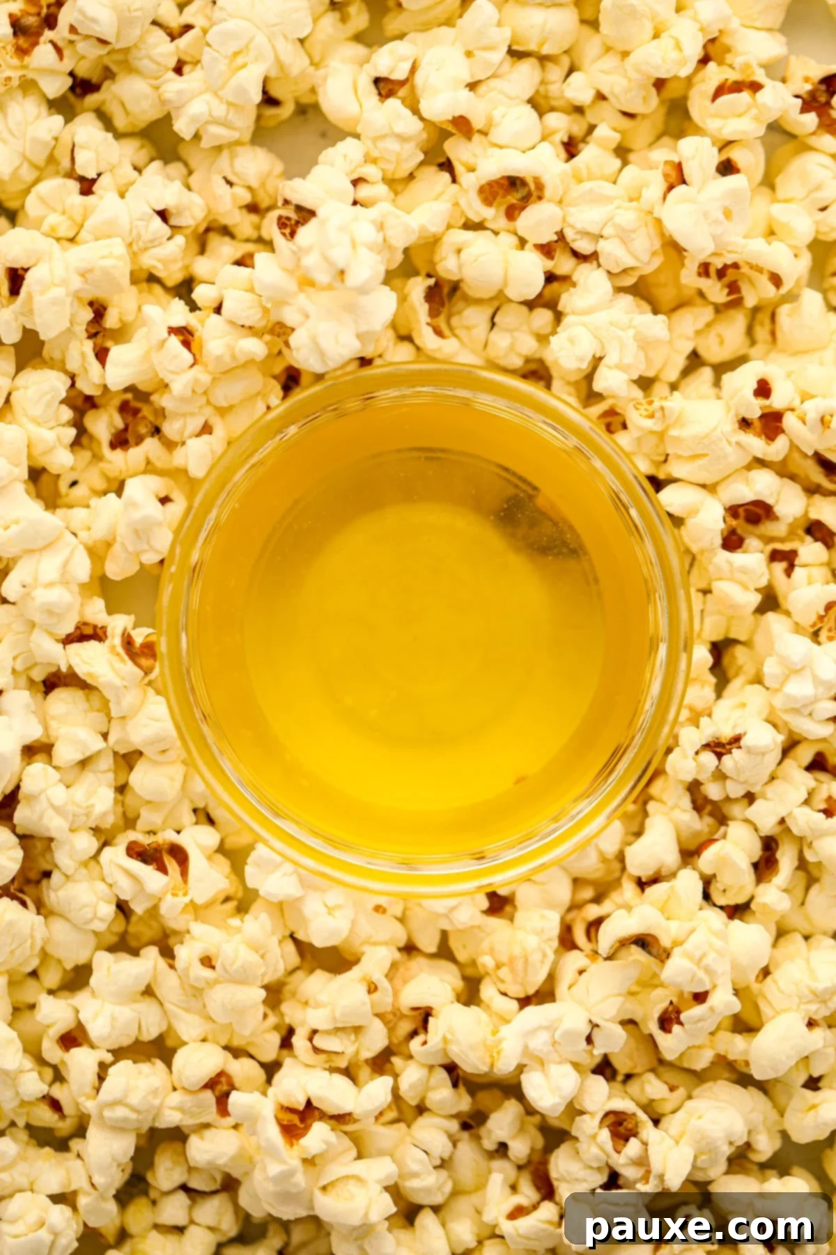 Golden Popcorn Topping 8 A small bowl of clarified butter in the middle of buttery popped popcorn.