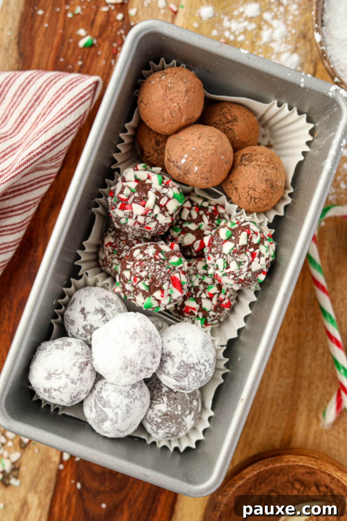 Refreshing Peppermint Truffles 9 A metal loaf pan filled with homemade truffles; one coated with cocoa powder, another with crushed candy canes, and a third with powdered sugar.