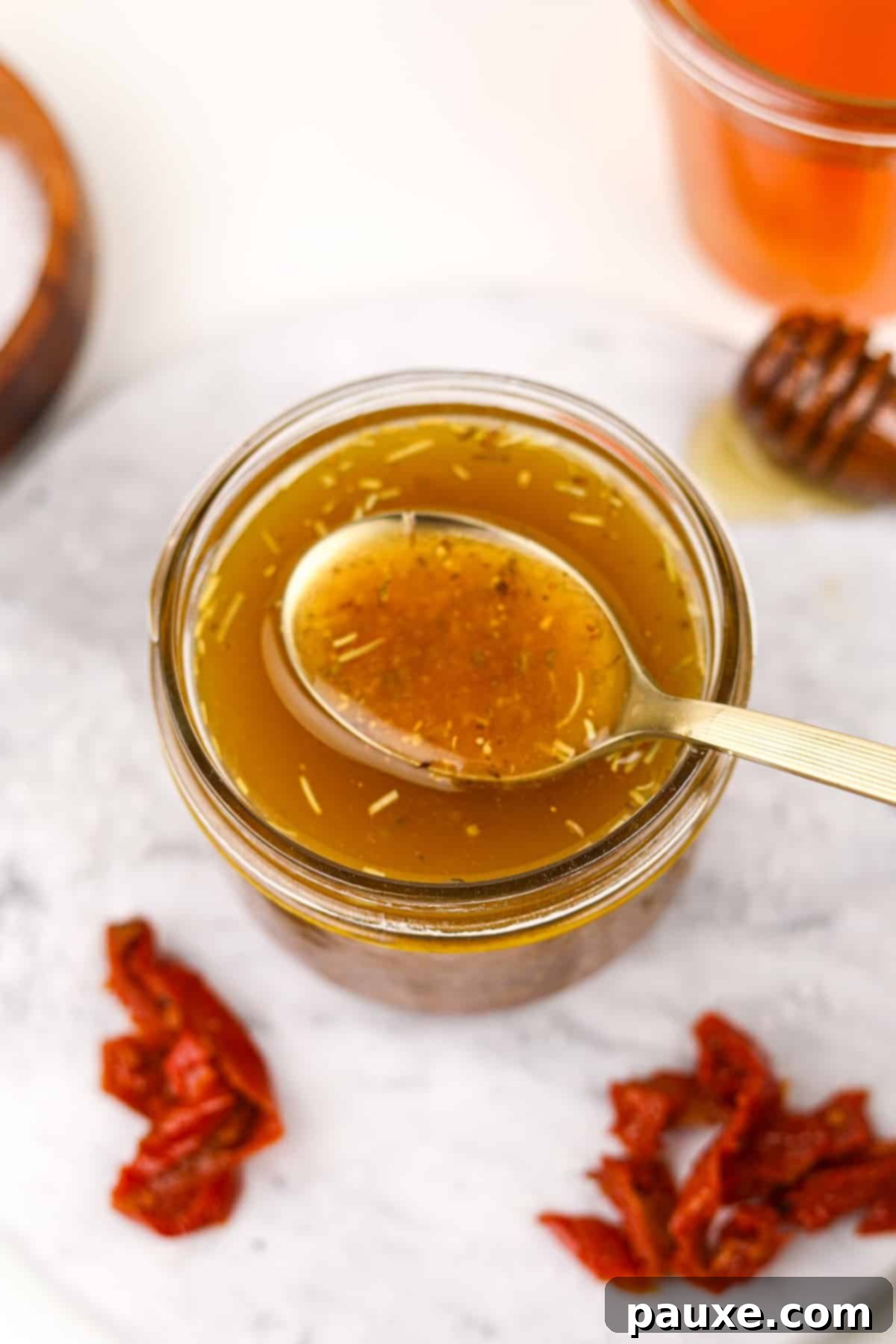 Mediterranean Sunset Vinaigrette 2 A gold spoon taking a small amount of homemade dressing from a jar.