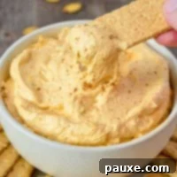 A serving bowl of pumpkin fluff dip, with a graham cracker being dipped in.