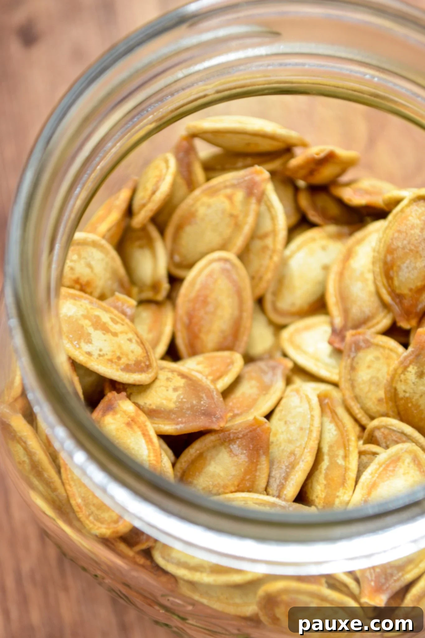Crispy Air Fryer Pumpkin Seeds 10 A pristine clear glass jar, filled to the brim with beautifully golden and crispy roasted pumpkin seeds, ready for snacking.