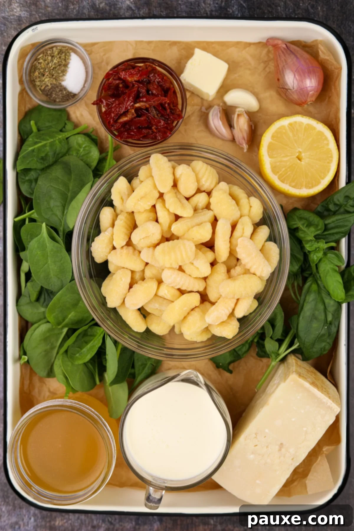 Rustic Tuscan Gnocchi 3 A flat lay photograph of the ingredients needed to make tuscan gnocchi, including broth, cream, parmesan, and sun-dried tomatoes.