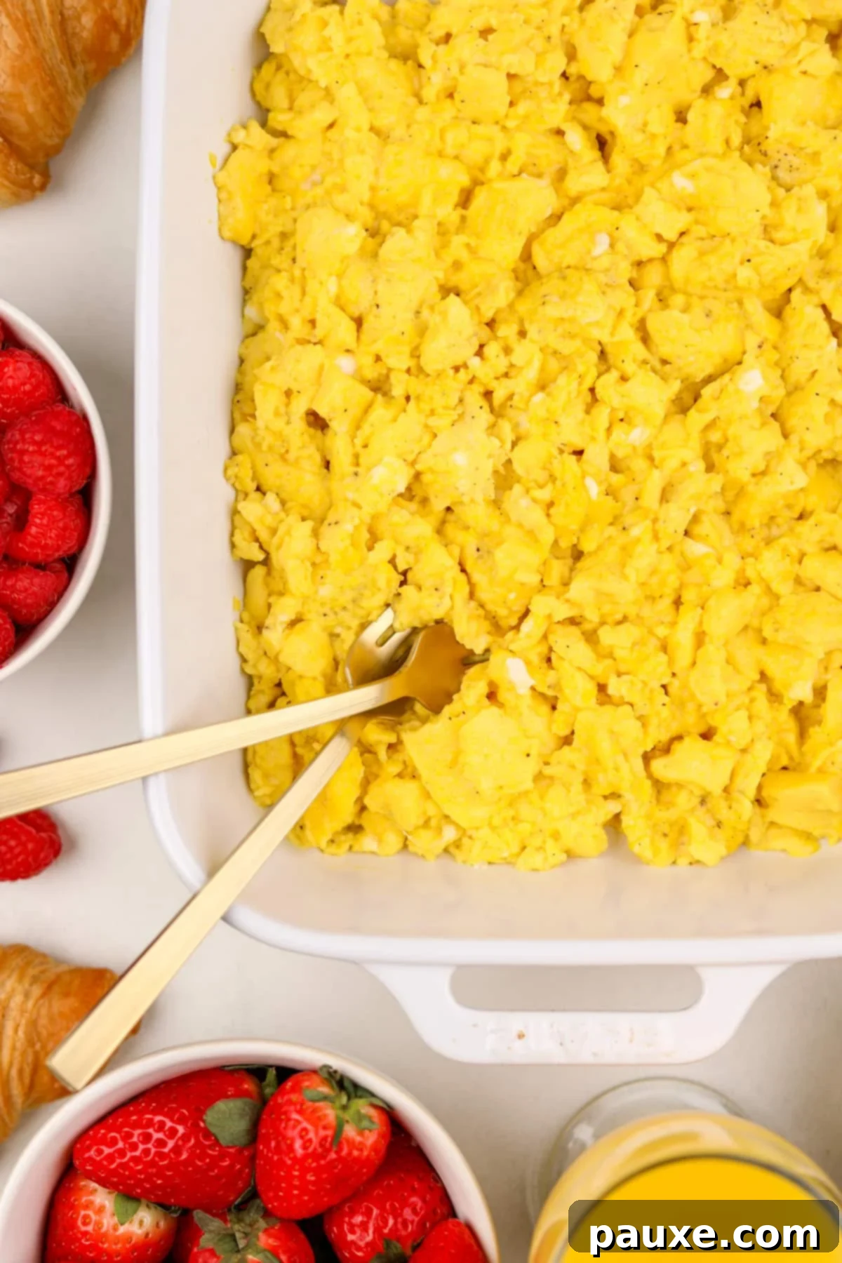Fluffy Oven Scramble 2 A close up of a baking dish with fluffy baked scrambled eggs and two gold forks fluffing them.
