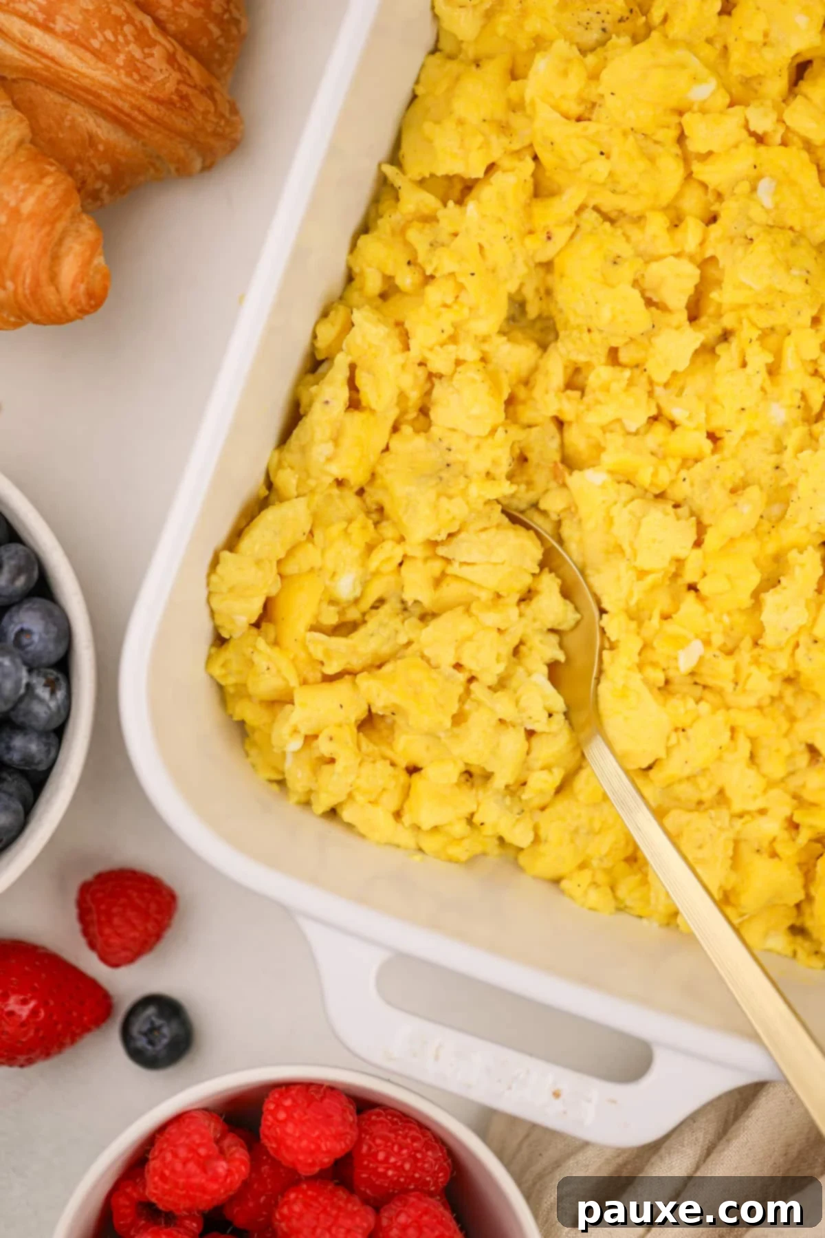 Fluffy Oven Scramble 6 A gold spoon scooping scrambled eggs from a baking dish.