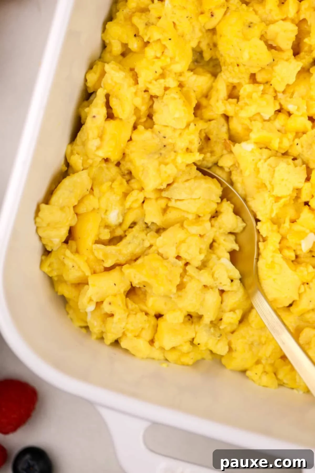 Fluffy Oven Scramble 7 Scooping scrambled eggs from a baking dish.